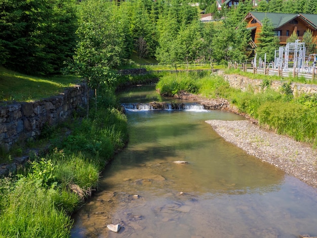 Piccolo fiume con rapide a bukovel ucraina ripresa del flusso del fiume creato artificialmente con otturatore lento l'acqua del fiume risplende al sole