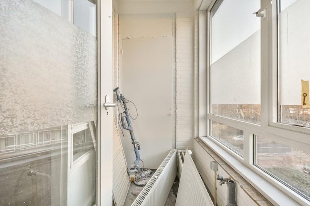 A small room under renovation with large bright windows and building materials