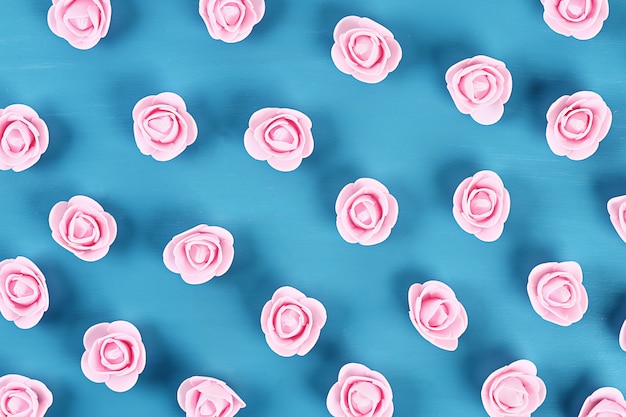 Small roses on blue background. Top view. Summer background. Flat lay.