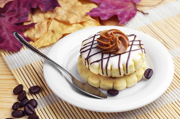 Small round cake with icing and chocolate on wooden table