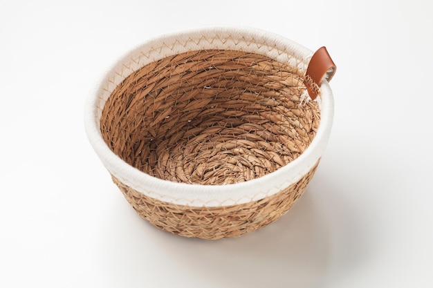 Small round seagrass and white cotton rope storage basket with rim on white background