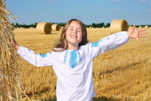 Foto piccola ragazza rurale sul campo di raccolta con balle di paglia
