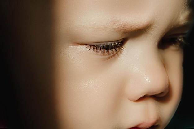 Маленький грустный мальчик с опущенными глазами и ресницами Милый ребенок с нахмуренными бровями