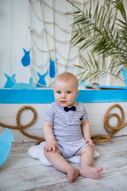 Small sailor sits near a blue and white boat on a wall with a marine decor