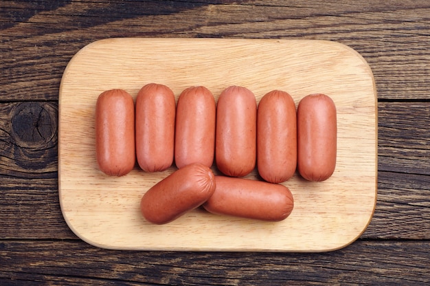 Small sausages on wooden cutting board