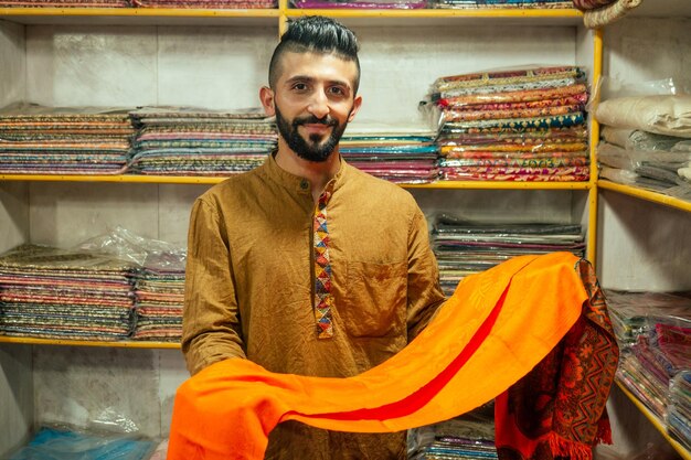 small shop owner indian man selling shawls at his store in arambol goa