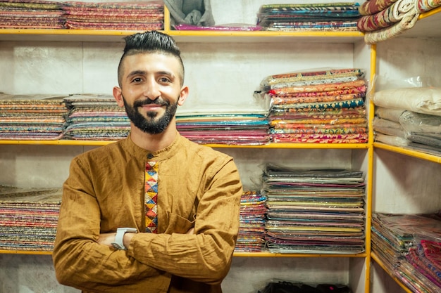 small shop owner indian man selling shawls at his store in arambol goa