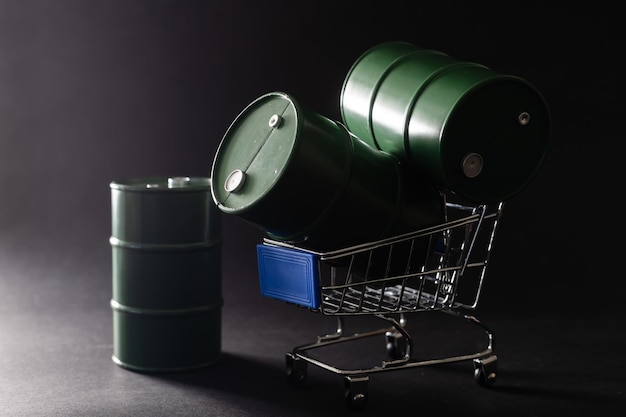 Small shopping cart and barrels isolated on dark background.