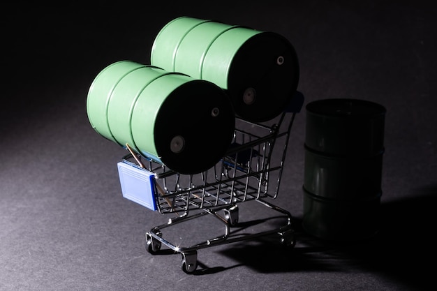 Small shopping cart and barrels isolated on dark background.