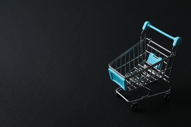 Small shopping cart on black space, space for text