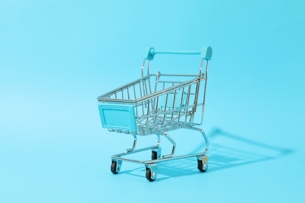 Small shopping cart on blue space, space for text