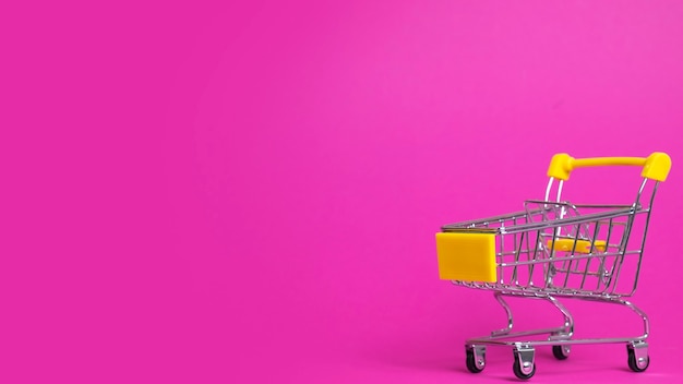 Small shopping cart on pink with copy space