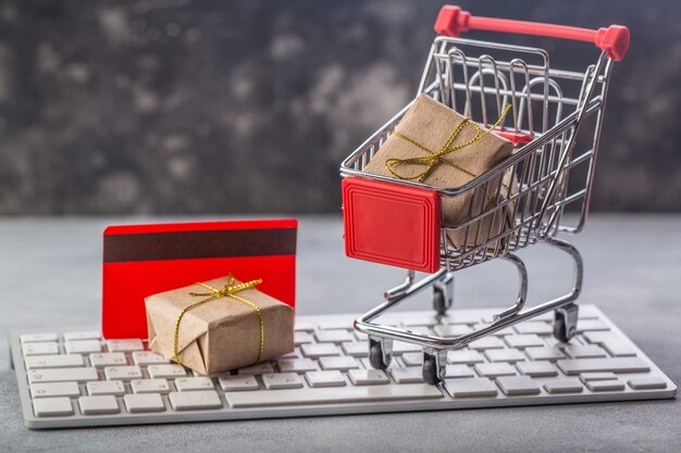 small shopping cart with presents and credit card on a laptop keyboard concepts