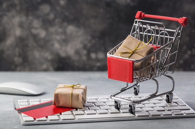 small shopping cart with presents and credit card on a laptop keyboard concepts