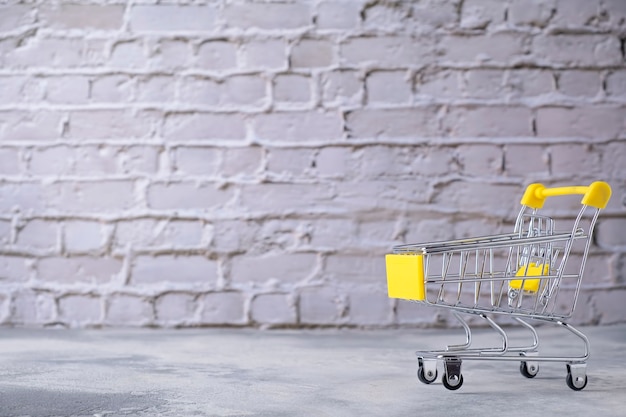 Photo small shopping trolley on grey background. text space