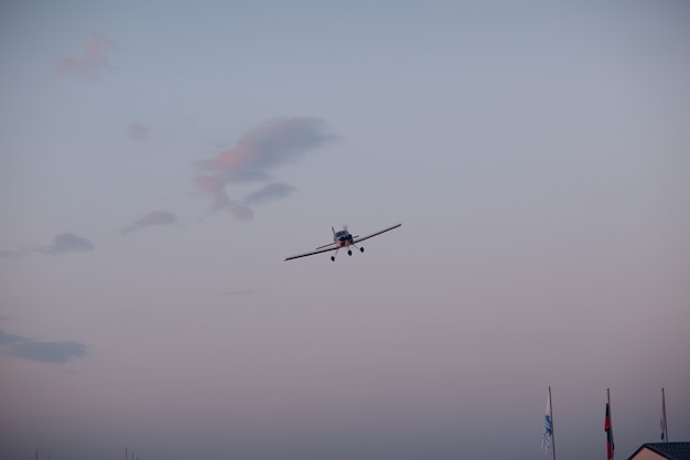 夕焼け空を背景に飛んでいる小さな単気筒飛行機。