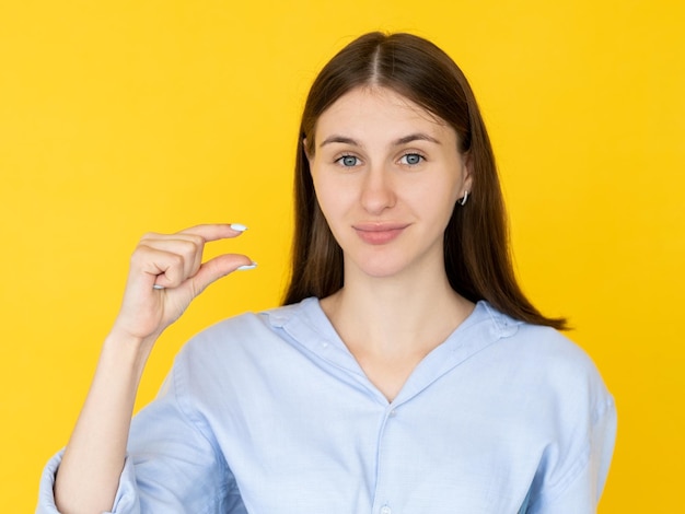 Photo small size pretty woman measurement gesture smiling cute brunette lady showing fingers sign of little bit isolated yellow