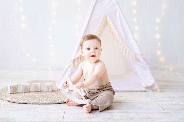 A small smiling baby boy playing in the nursery a bright cozy children's room natural textiles and wooden toys for the nursery