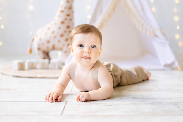 A small smiling baby boy playing in the nursery a bright cozy children's room natural textiles and wooden toys for the nursery