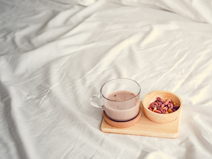 Photo 소금에 절인 콩과 핫 초콜릿으로 구성된 작은 간식이 침대에서 제공됩니다.
