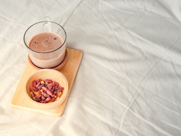 Small snacks set of salted beans and hot chocolate served on the bed