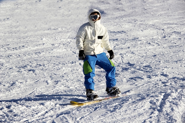 Small snowboarder on blue sky backdrop.