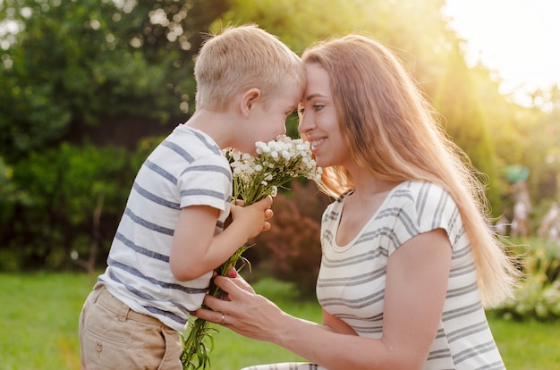 Small son gives his mother a bouquet of delicate flowers.