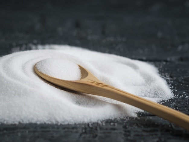 Small spoon of light wood filled with salt finely.