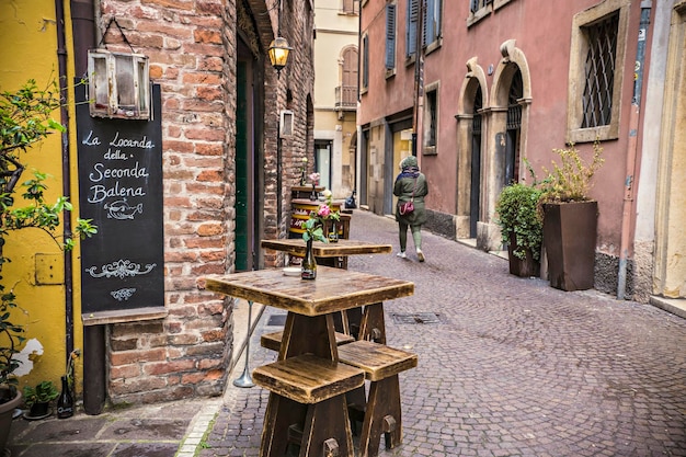 Small street cafe exterior, historical street of Verona old town. Street bar with tables and umbrell