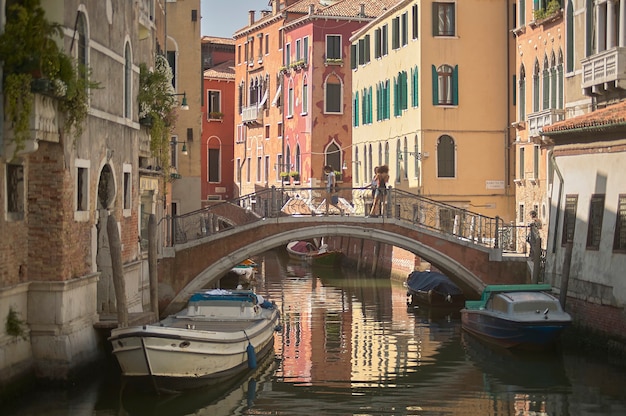 Piccola via di venezia con edifici storici che si affacciano direttamente su un piccolo corso d'acqua e uniti da un ponte.