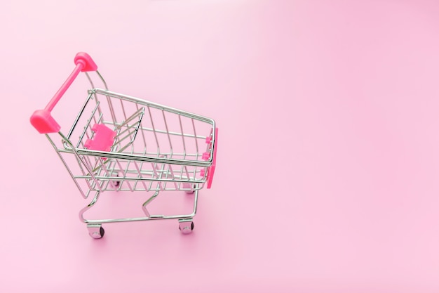 Фото Небольшой супермаркет продуктовых тележка для покупок, изолированных на розовом фоне