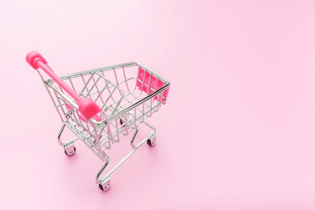 Small supermarket grocery toy push cart isolated on pink pastel colorful background