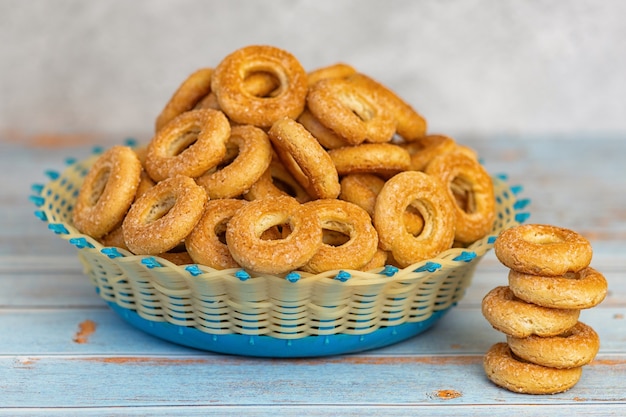 Small sweet bagels in a wicker bowl on light blue wooden.