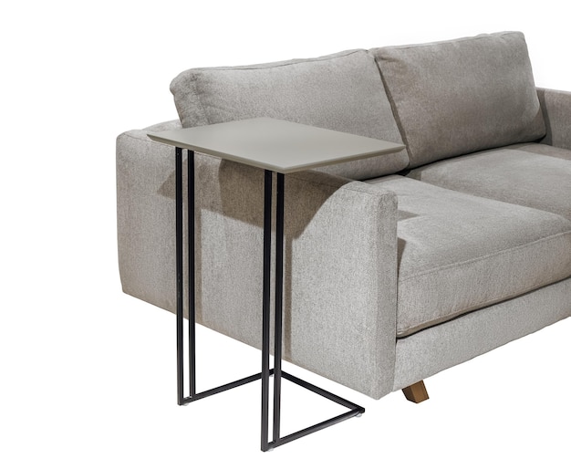 A small table is next to a couch that has a metal base.