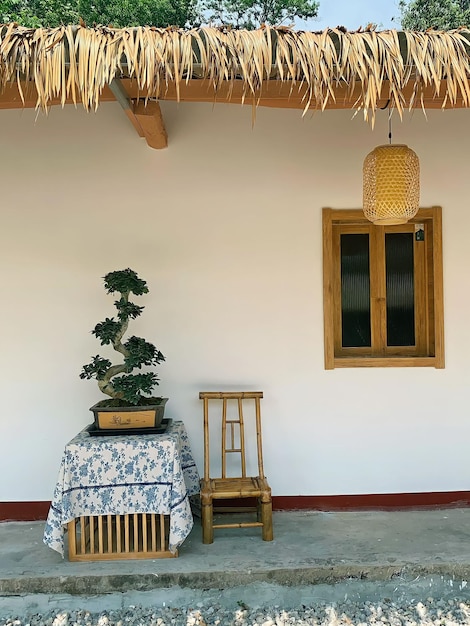 A small table with a bamboo chair and a small potted plant on it.