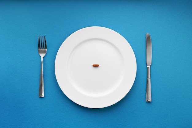 A small tablet in a plate. Medical concept. Eat pills instead of food.