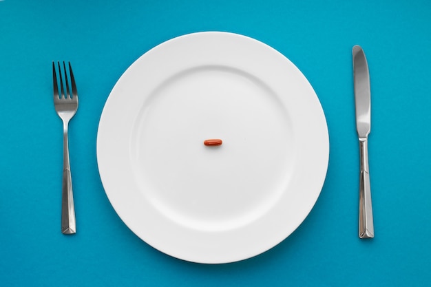 A small tablet in a plate. Medical . Eat pills instead of food.