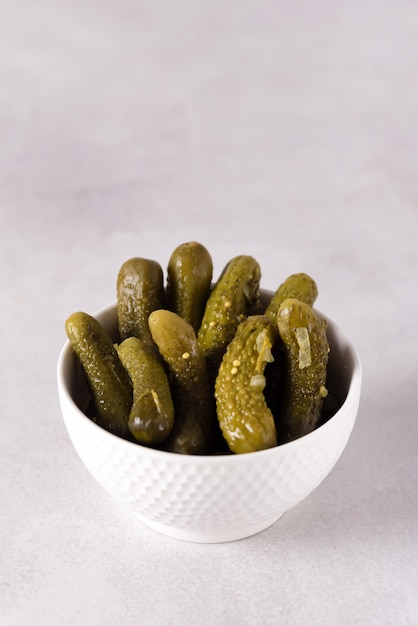 Small tasty pickled cucumbers Traditional recipe served in a ceramic white bowl gherkins