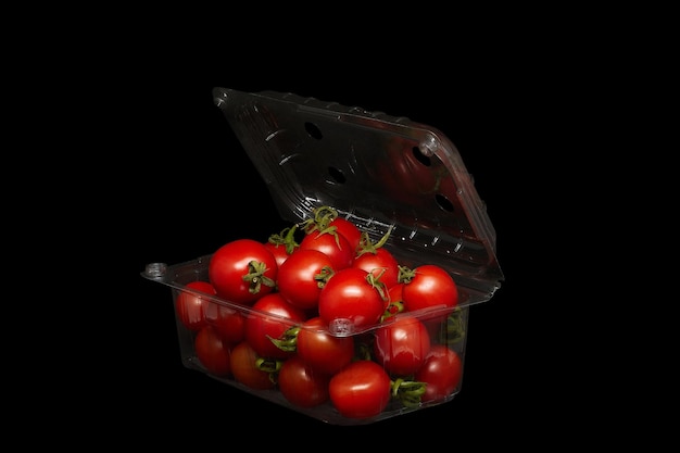 Small tomatoes in plastic packaging on a black background