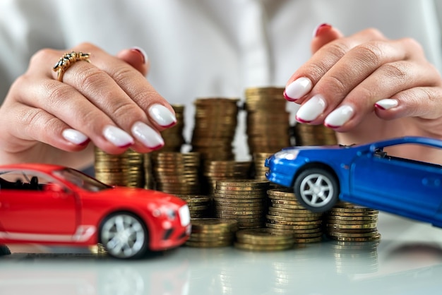 Small toy cars with a mountain of coins and protection arms on top saving money credit concept Car insurance against accidents on the road