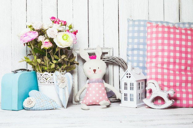 작은 장난감 집, 조랑말, 장난감 토끼, 나무 배경의 어린이 방에 있는 베개