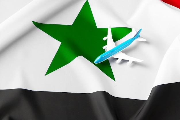 Small toy plane over the fabric flag of Syria