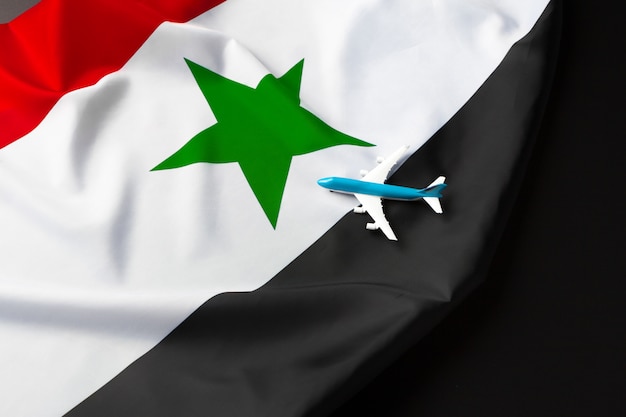 Small toy plane over the fabric flag of Syria