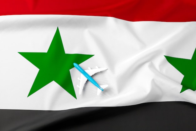 Small toy plane over the fabric flag of Syria