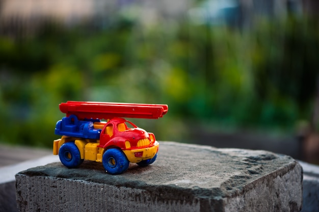 Small toy truck with crane stands on foam block on green grass .