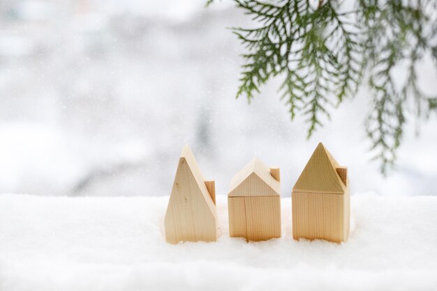 Small toy wooden houses made of timber in snow. New Year, Christmas background in eco friendly style