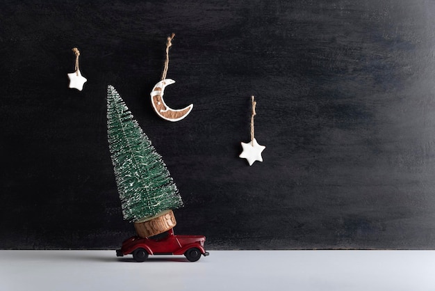 작은 나무는 검정색 배경의 모형 자동차 위에 서 있습니다. 새해에는 24시간 배달됩니다.