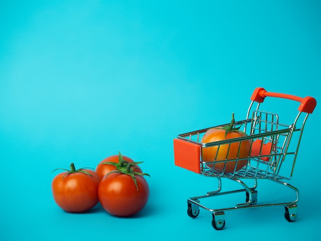 Small trolley with tomatoes on a blue background