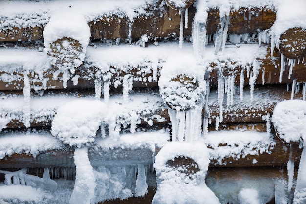 冬の雪の下で小さな丸太の背景の小さな壁