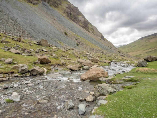 Small waterfall along back road in countryside landscape view in England under cloudy sky